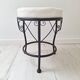 Black iron stool/pouf with its boucle fabric cushion.