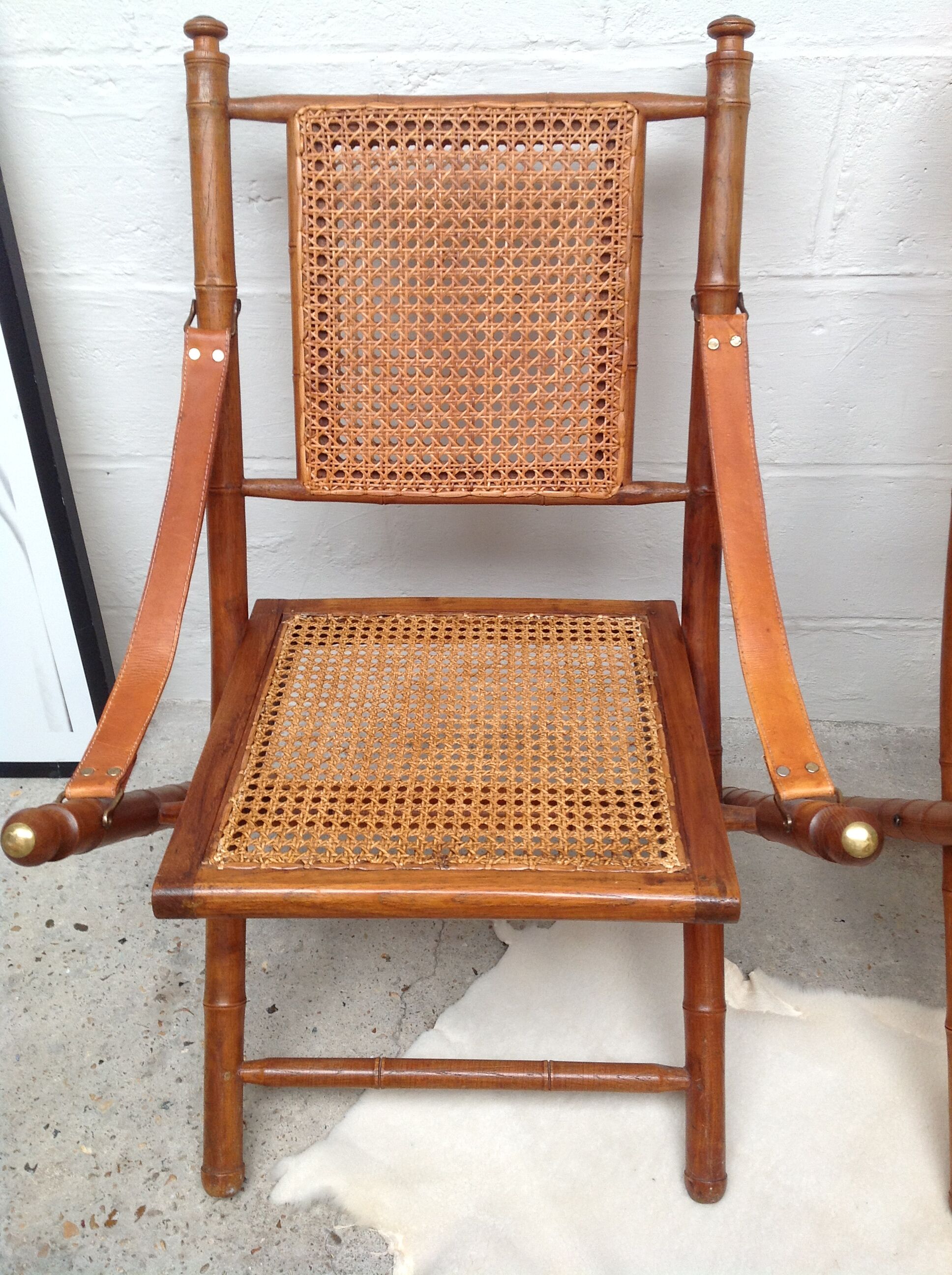 Pair of folding chairs in bamboo and caning, leather and brass