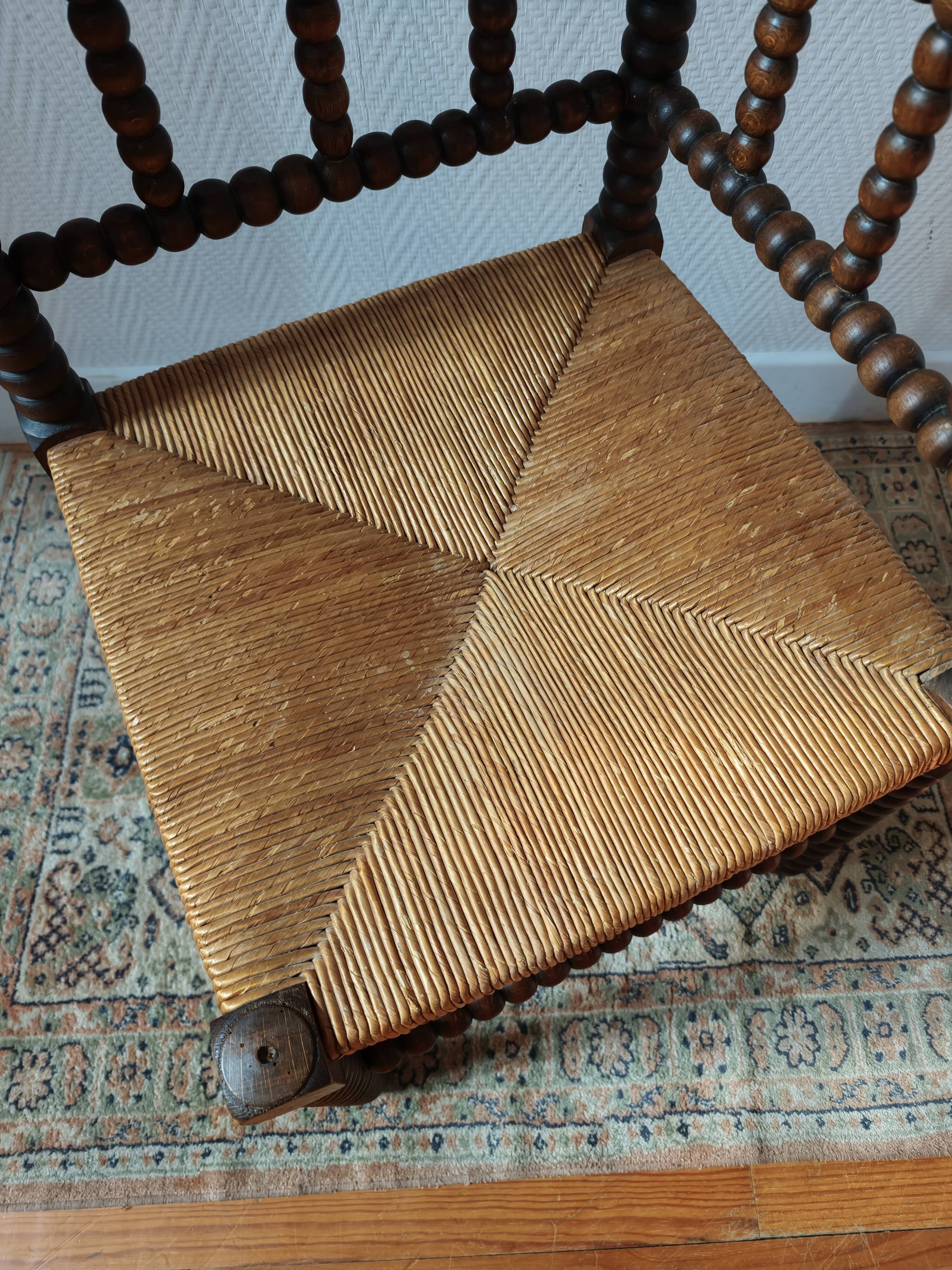 Old wooden turned spindle fireside chair with a straw seat.