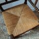 Old wooden turned spindle fireside chair with a straw seat.