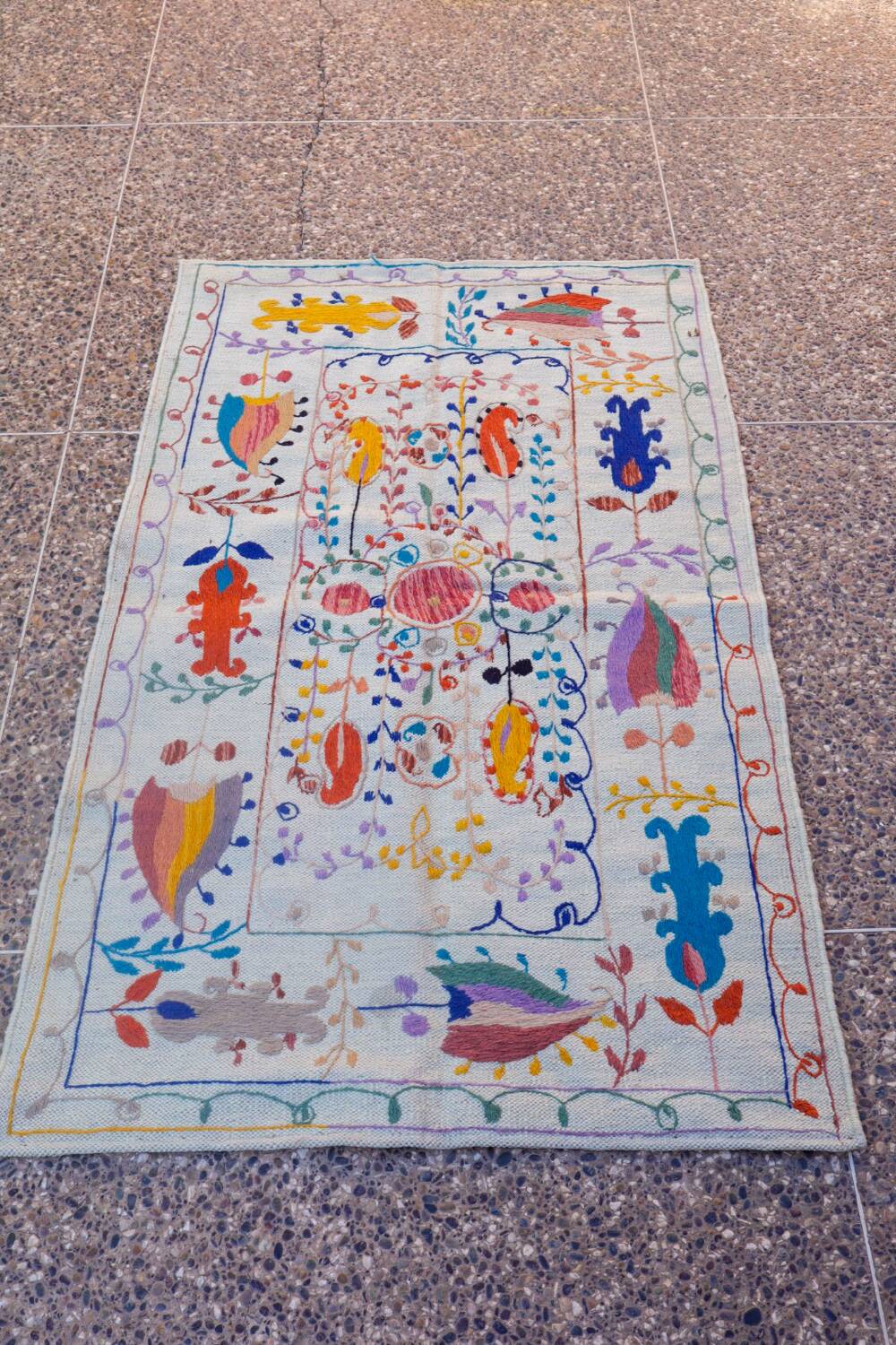 White suzani kilim rug with embroidered colorful patterns