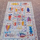 White suzani kilim rug with embroidered colorful patterns