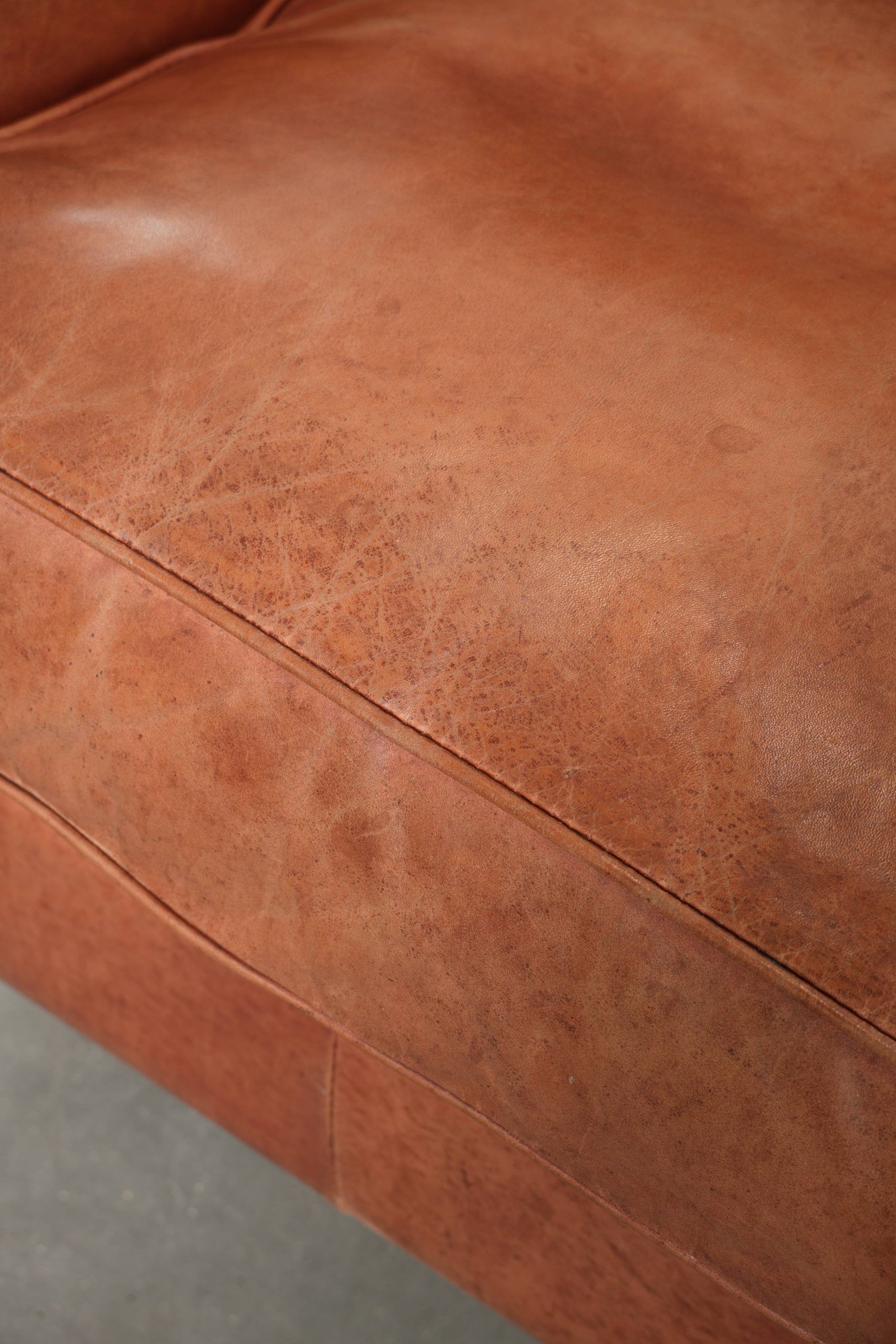 Light cognac-coloured cow leather wingback armchair with matching piping