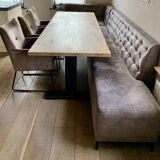Dining table made of wood with three leather seats and a long leather sofa.