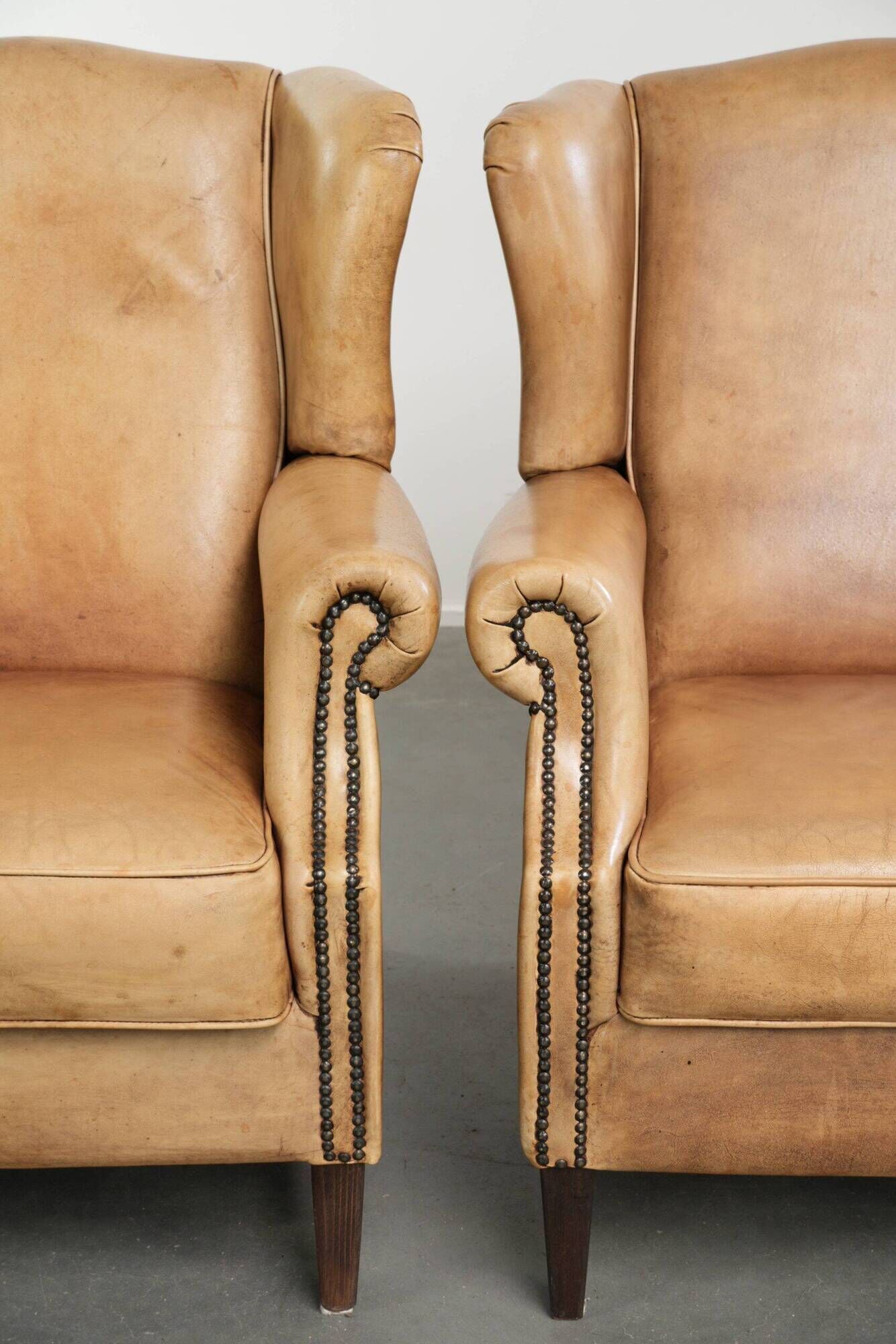 Set of two light cowhide wingback armchairs with a timeless English look