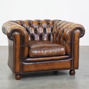 A well-maintained cowhide leather English Chesterfield armchair