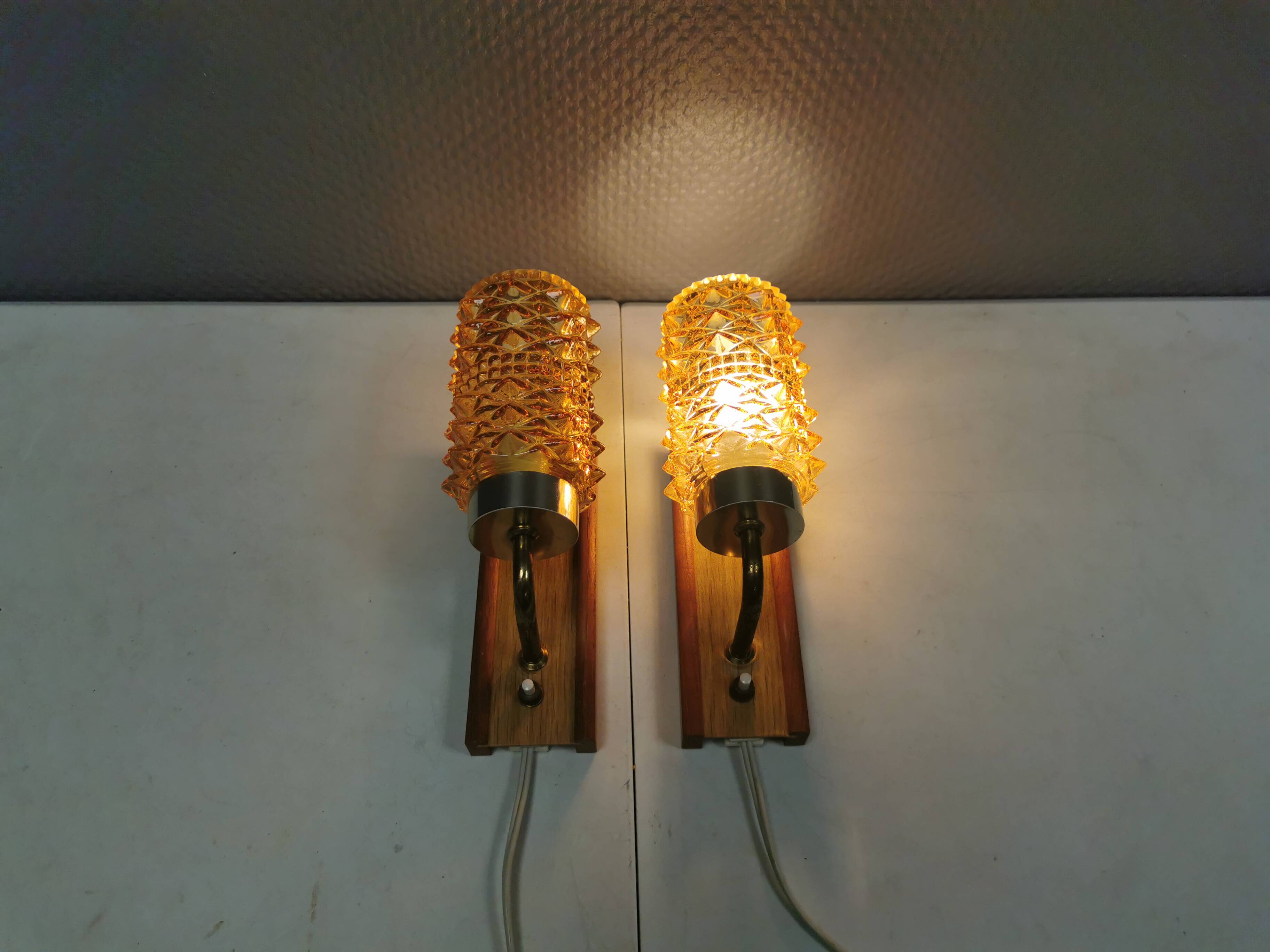 A set of wall lamps in teak wood, with amber colored glass