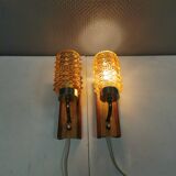 A set of wall lamps in teak wood, with amber colored glass