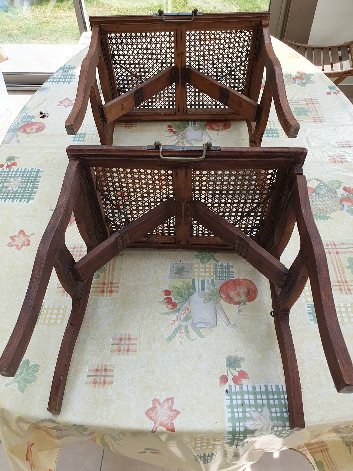 Two folding stools with caned seats.