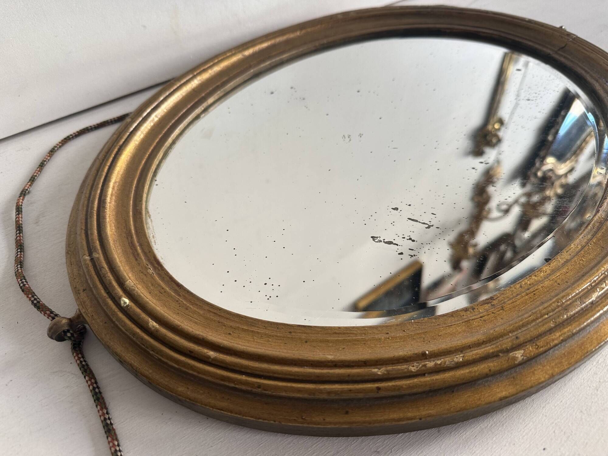 Antique oval mirror in gilded wood, bevelled mercury glass, 19th century.