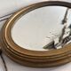 Antique oval mirror in gilded wood, bevelled mercury glass, 19th century.