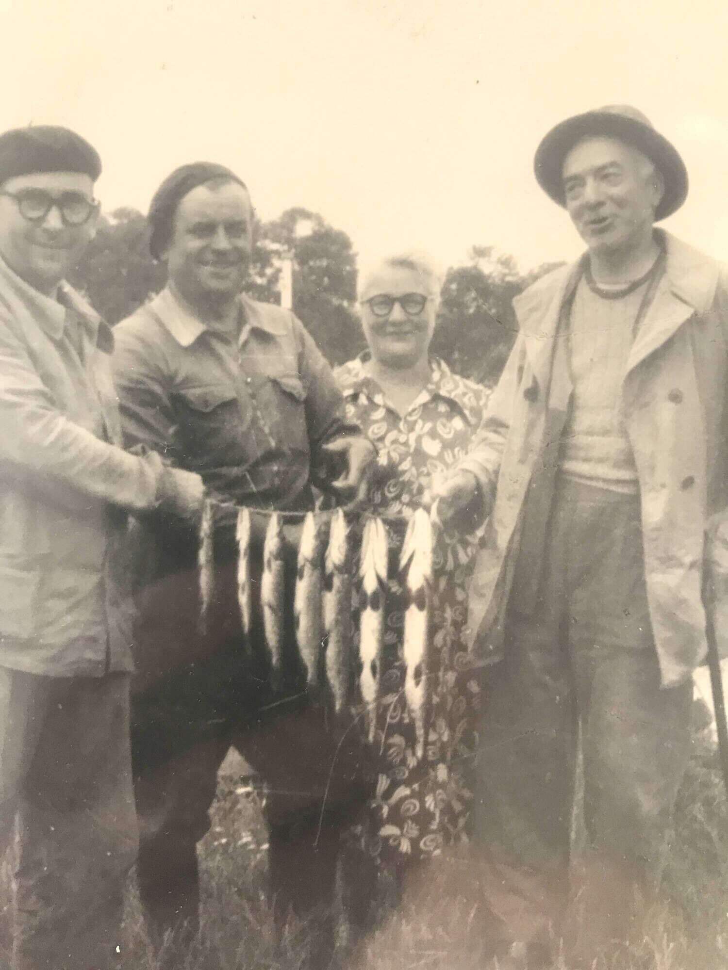 Fishing trophy with radiant faces, c. 1950. Black and white photograph.