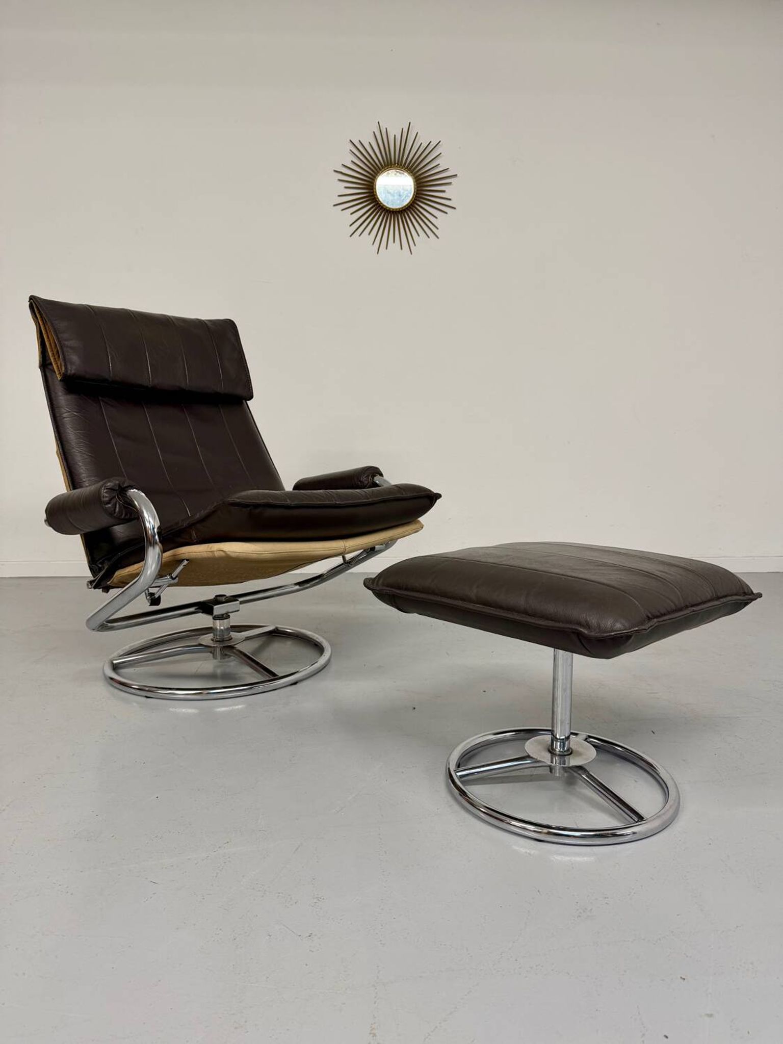 Vintage leather reclining armchair and its 1970s designer ottoman.