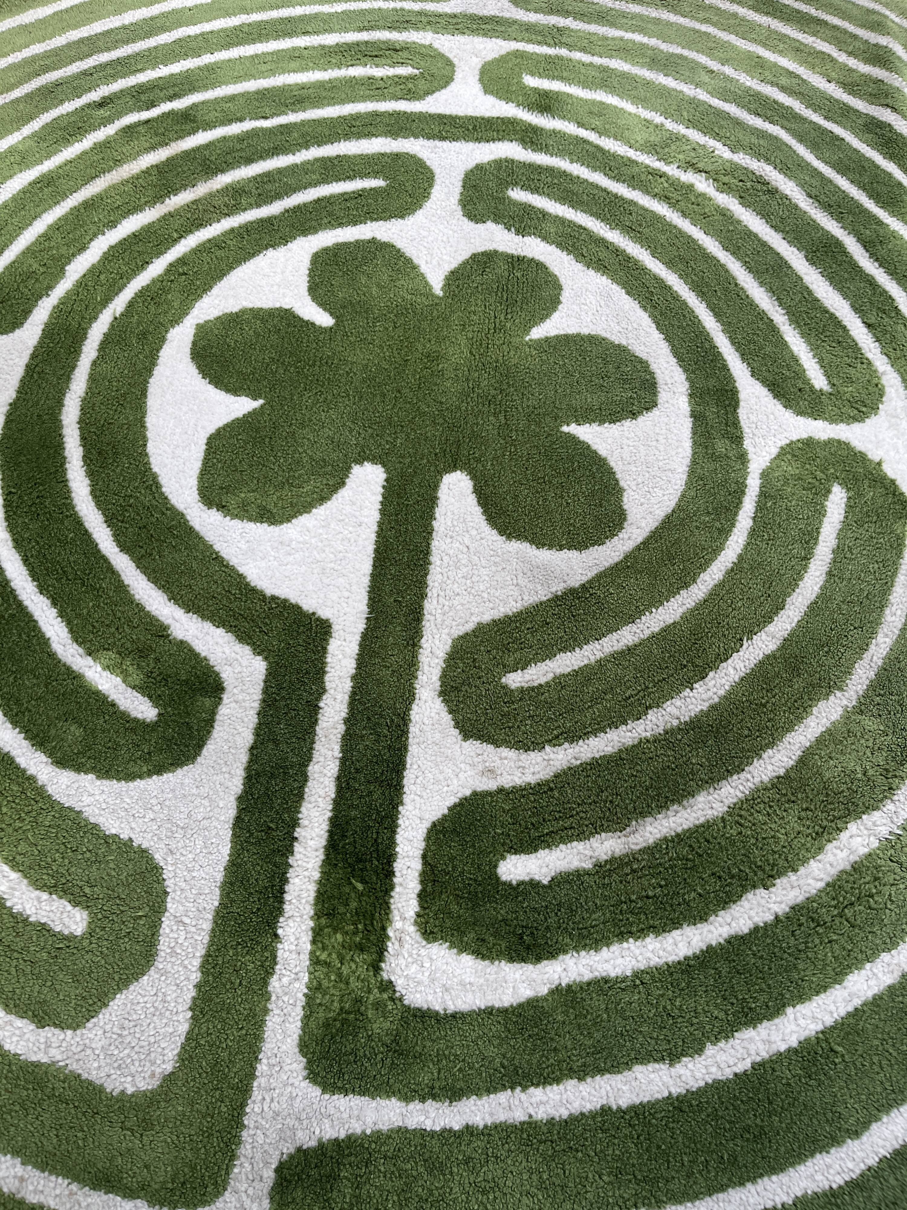 Circular rug with green decor on a cream background from the Labyrinth.