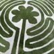 Circular rug with green decor on a cream background from the Labyrinth.