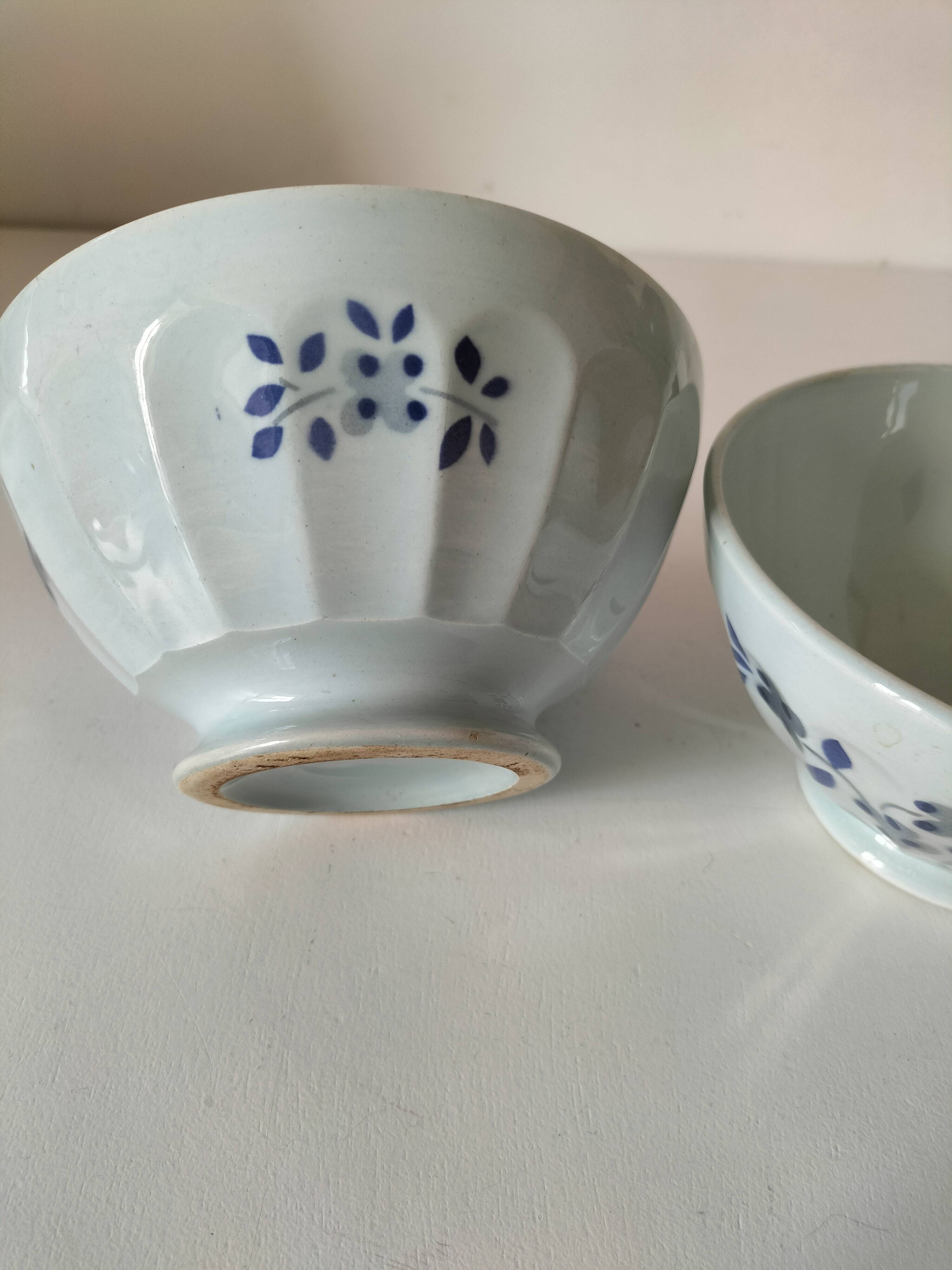 Two vintage farm bowls on a pale blue pedestal with floral decoration.