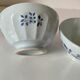 Two vintage farm bowls on a pale blue pedestal with floral decoration.
