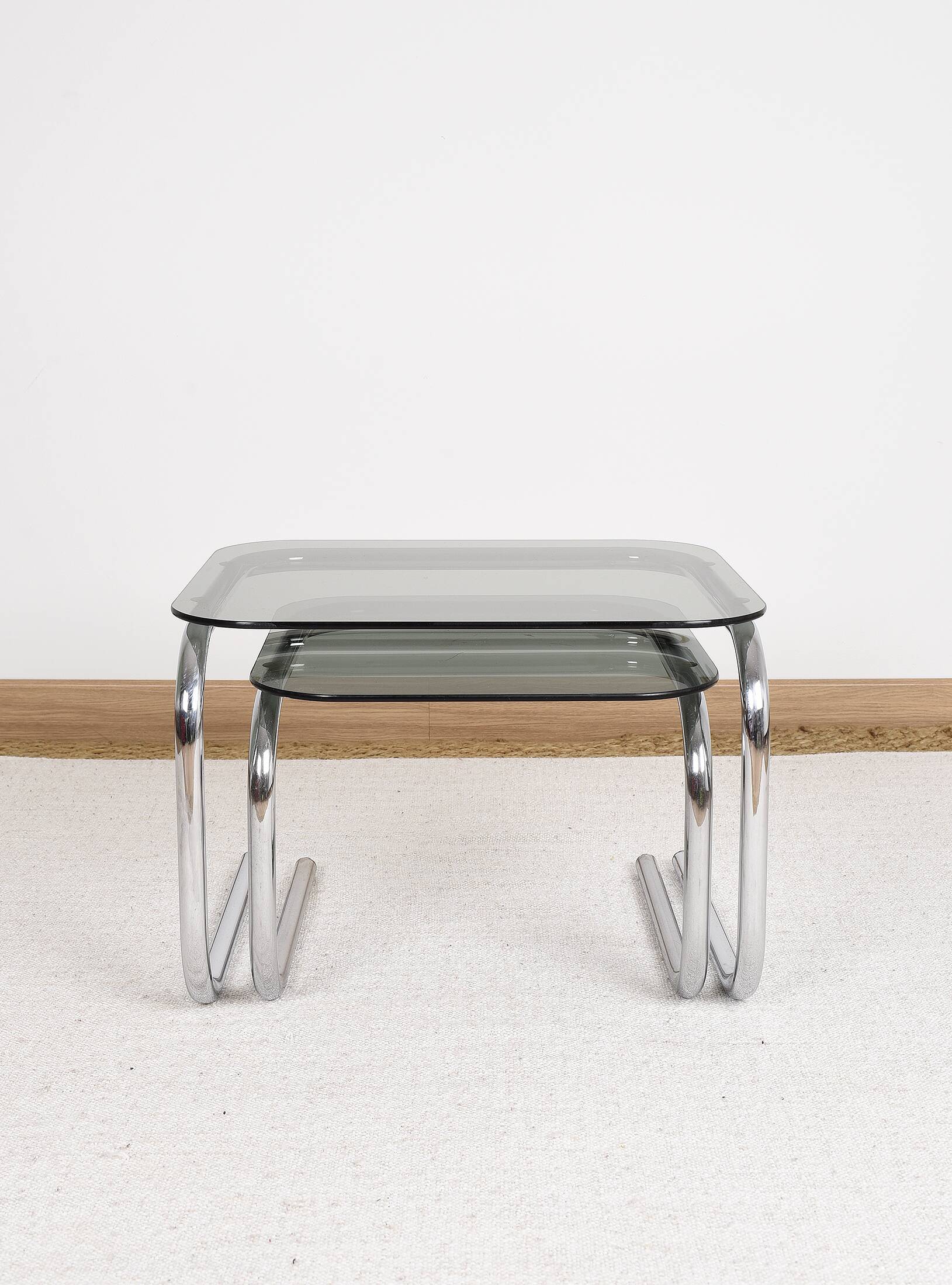 Pair of nesting tables in smoked glass and chrome legs.