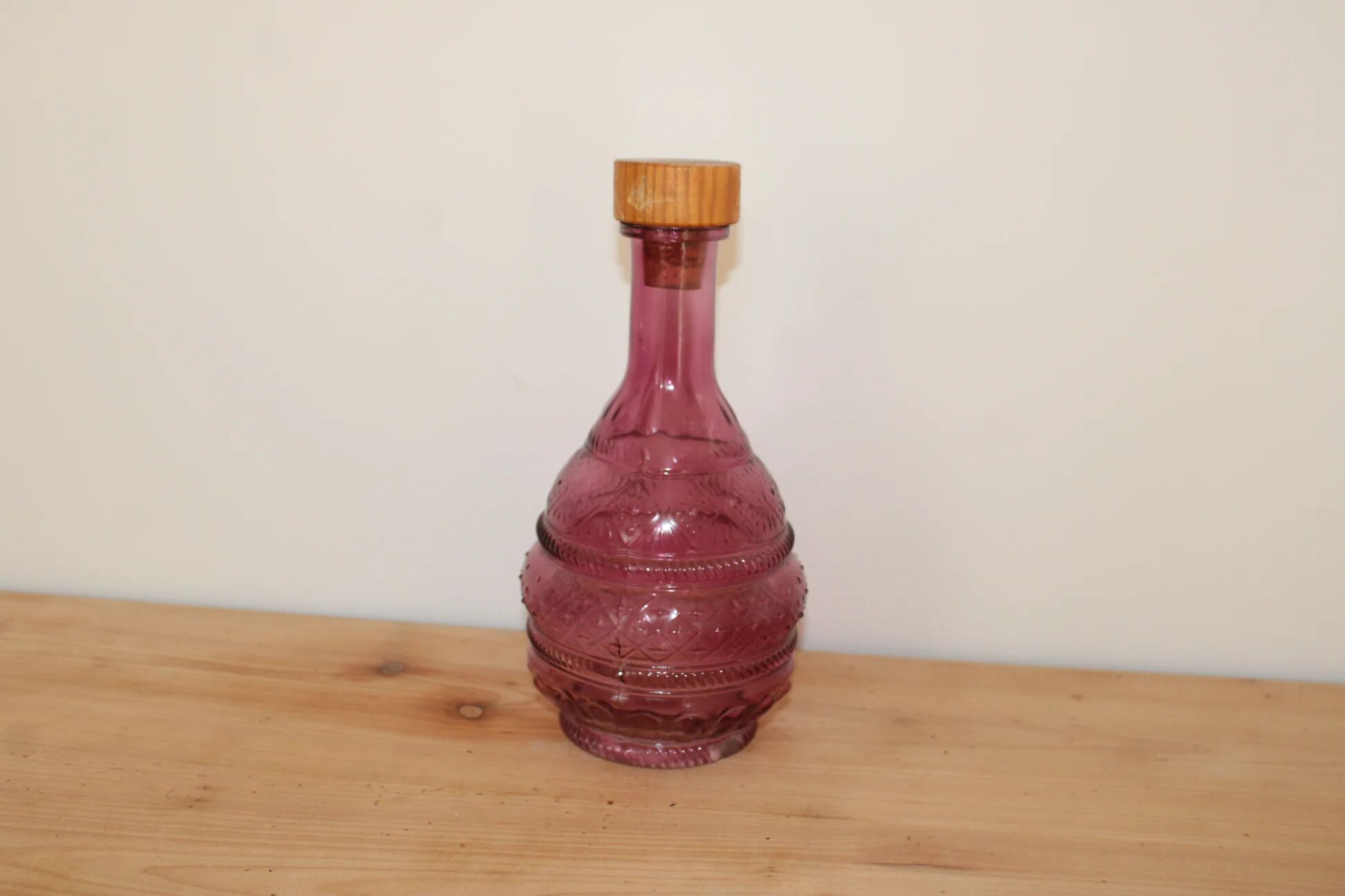 Vintage pink pressed glass carafe – retro decorative bottle with wooden stopper.