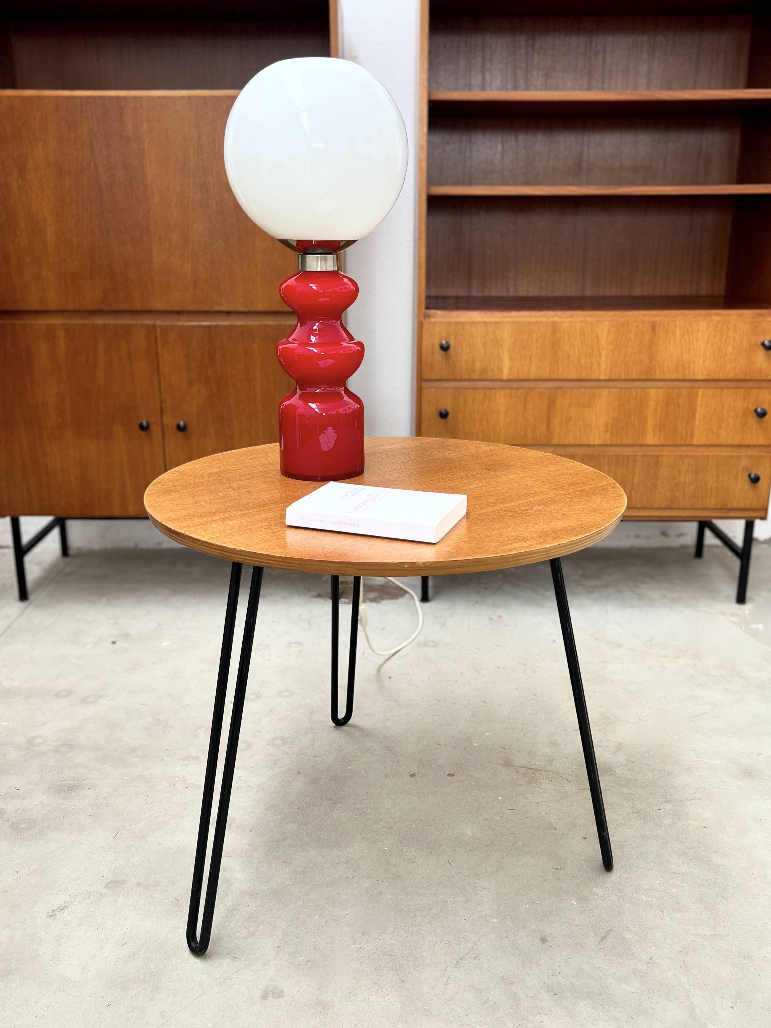Round side table with black lacquered metal hairpin legs.