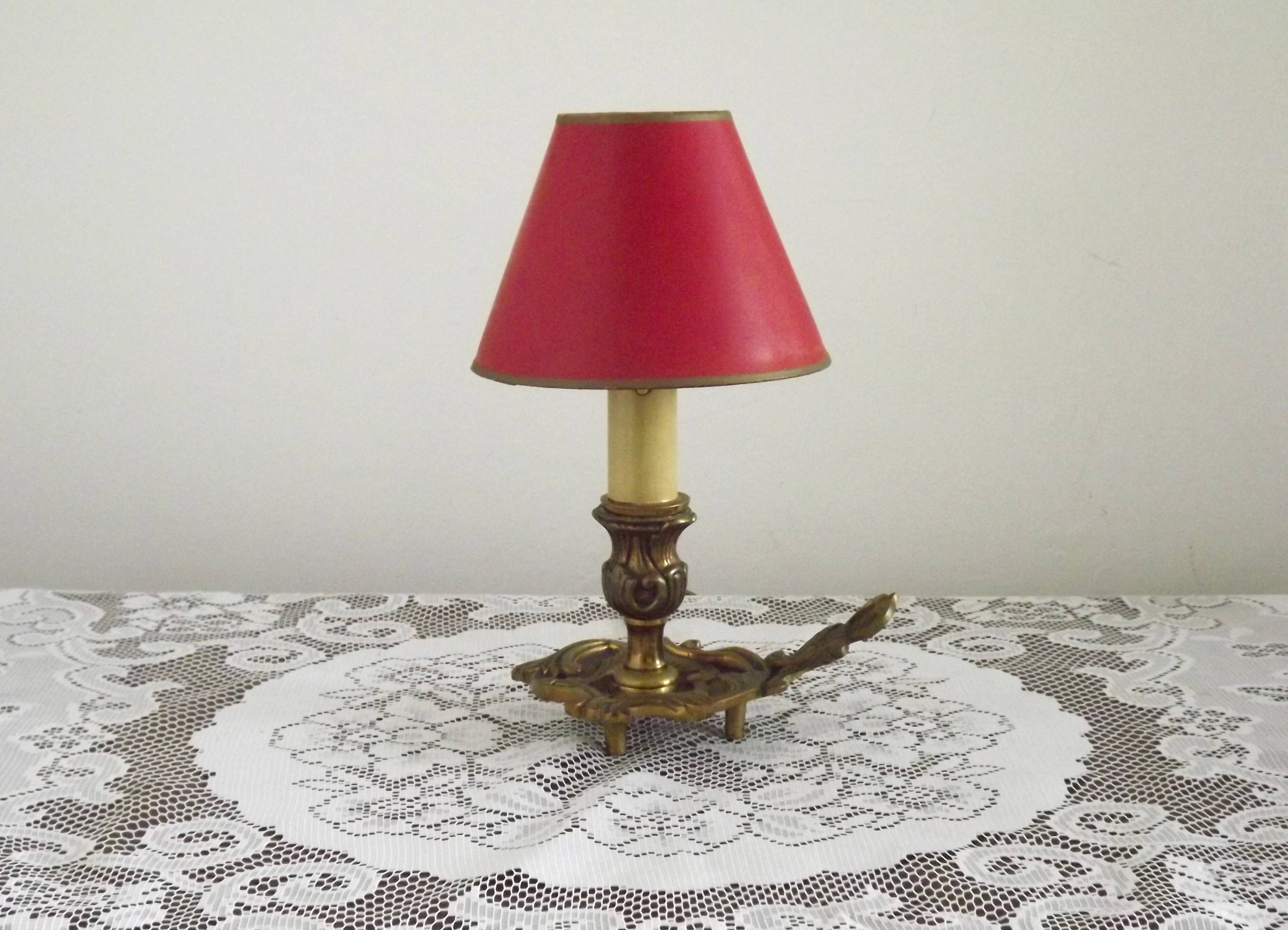 Vintage French bronze Wee Willie Winkie style lamp with red card shade.