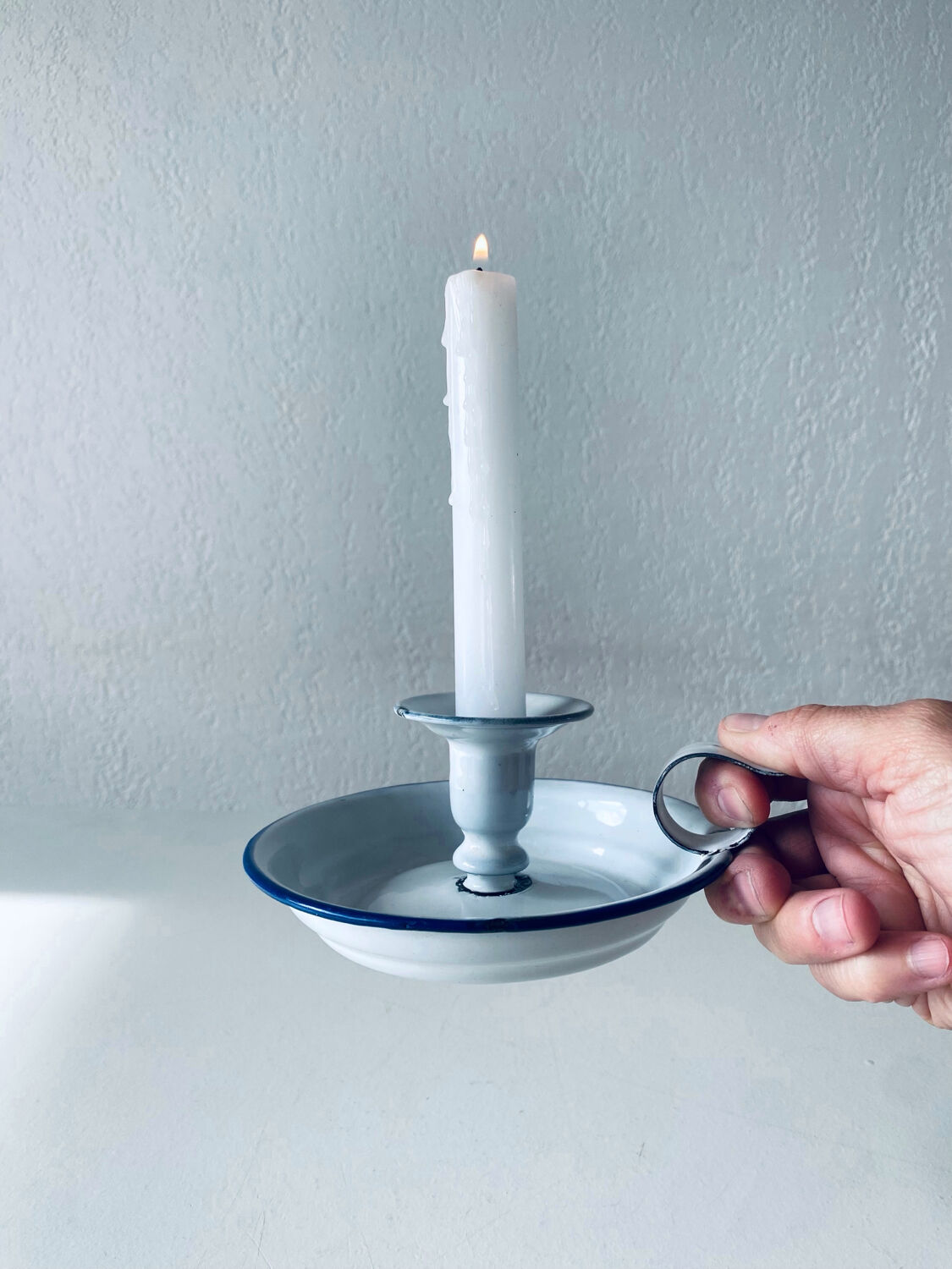 Old candle holder in white enameled metal
