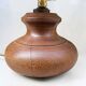 Vintage brutalist lamp with a wooden base and a cylindrical raffia shade.