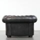 Ensemble composé d'un canapé chesterfield noir, d'un fauteuil et d'un pouf.