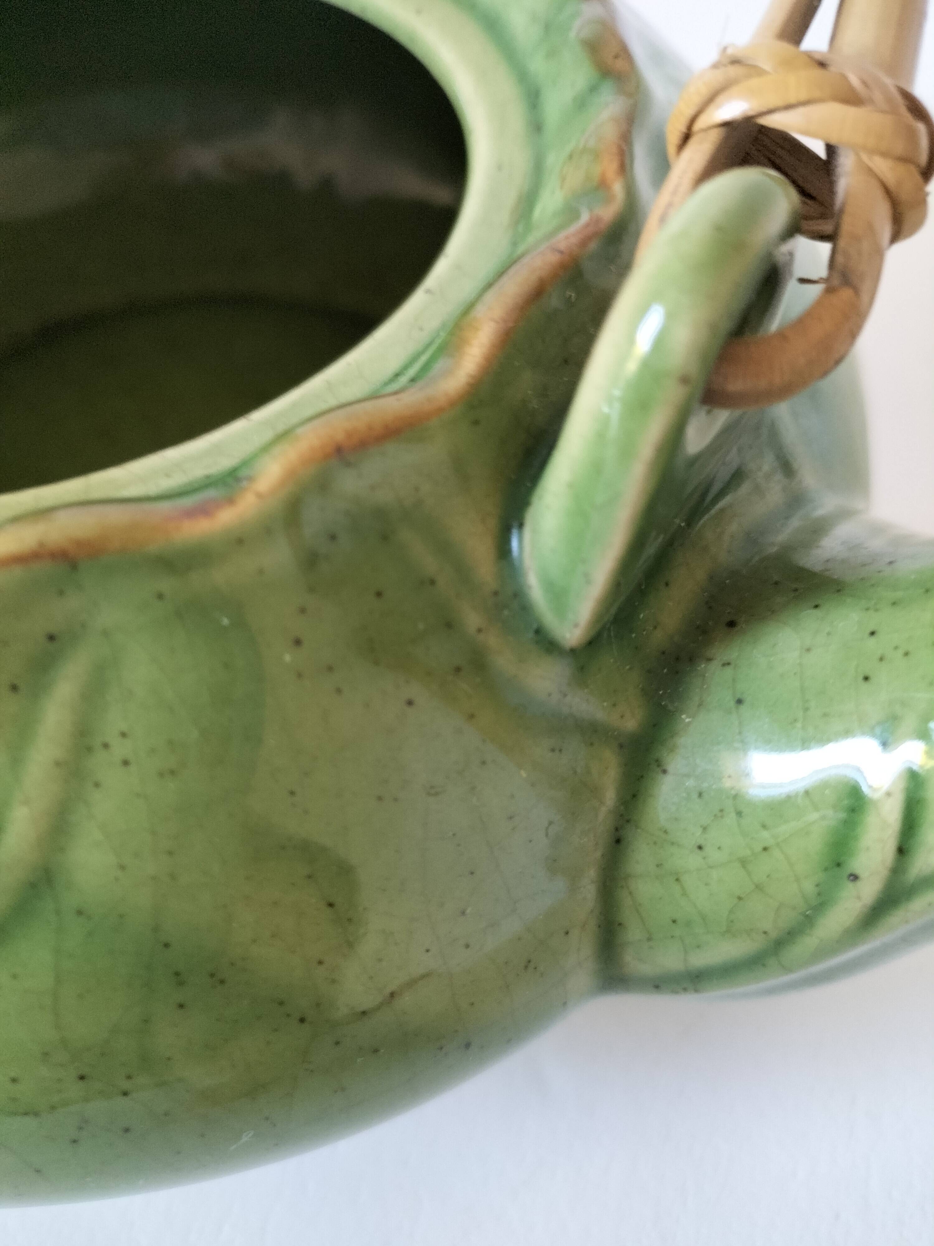 Vintage green teapot with lotus decoration and bamboo handle.