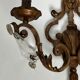 Pair of patinated wrought iron wall sconces with golden acanthus leaves and crystals.
