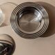 Vintage 1970s condiment pot made of glass and stainless steel with a lid, complete with a matching spoon.