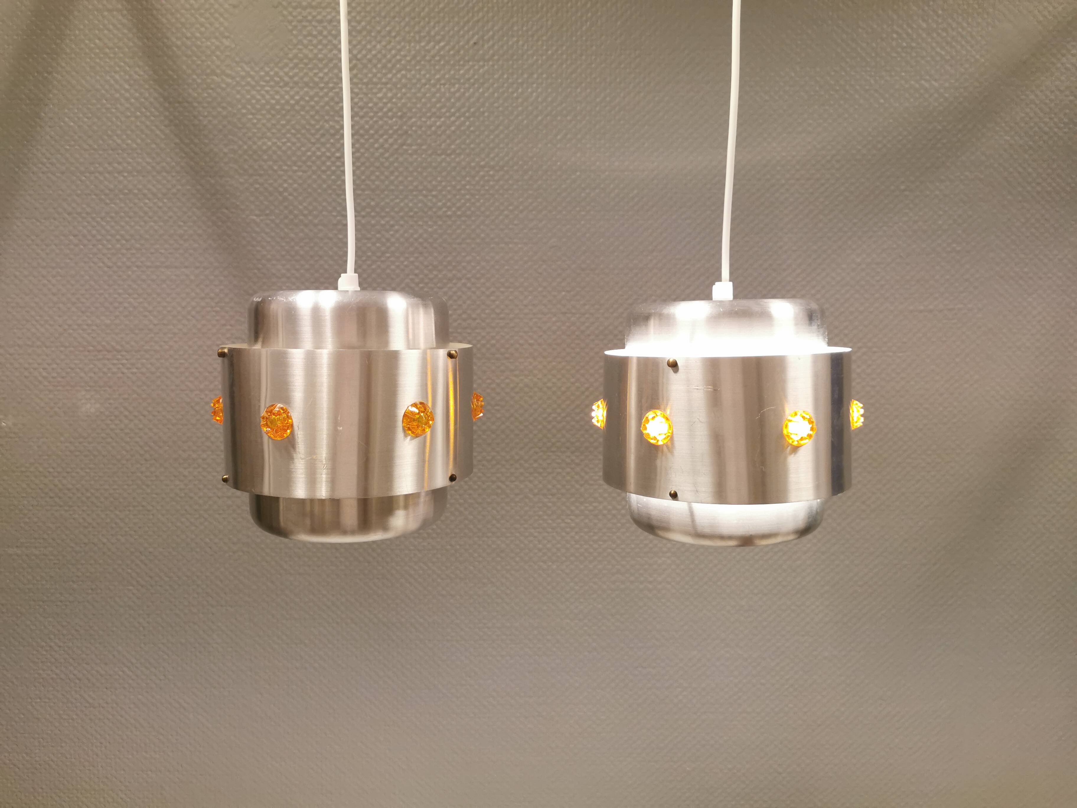 Two Space-Age hanging lamps, in silver-coloured aluminium with orange prisms.