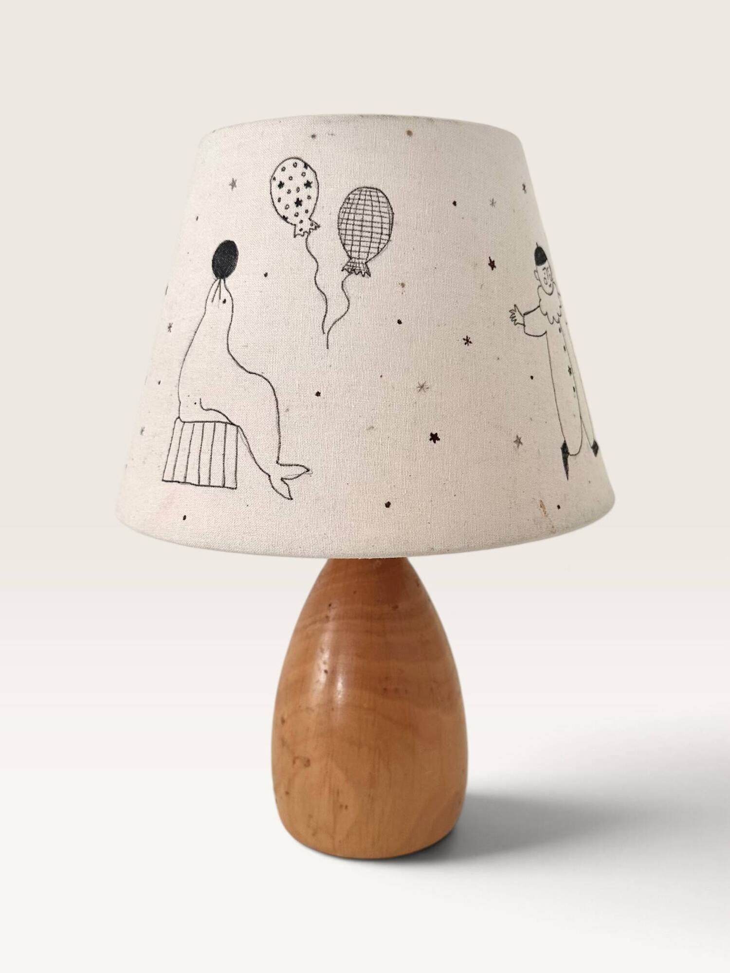 Wood-turned lamp with a hand-drawn lampshade, circus patterns.