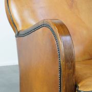 Unique, luxurious sheepskin armchair combined with wood and finished with decorative nails