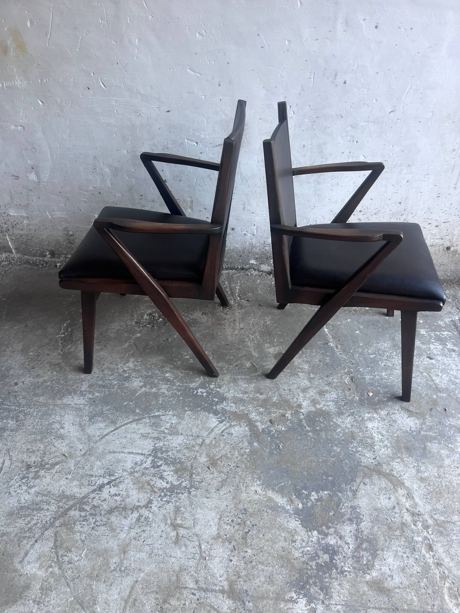 Pair of sculptural mid-century armchairs in dark wood and brown upholstery.