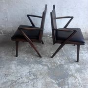 Pair of sculptural mid-century armchairs in dark wood and brown upholstery.