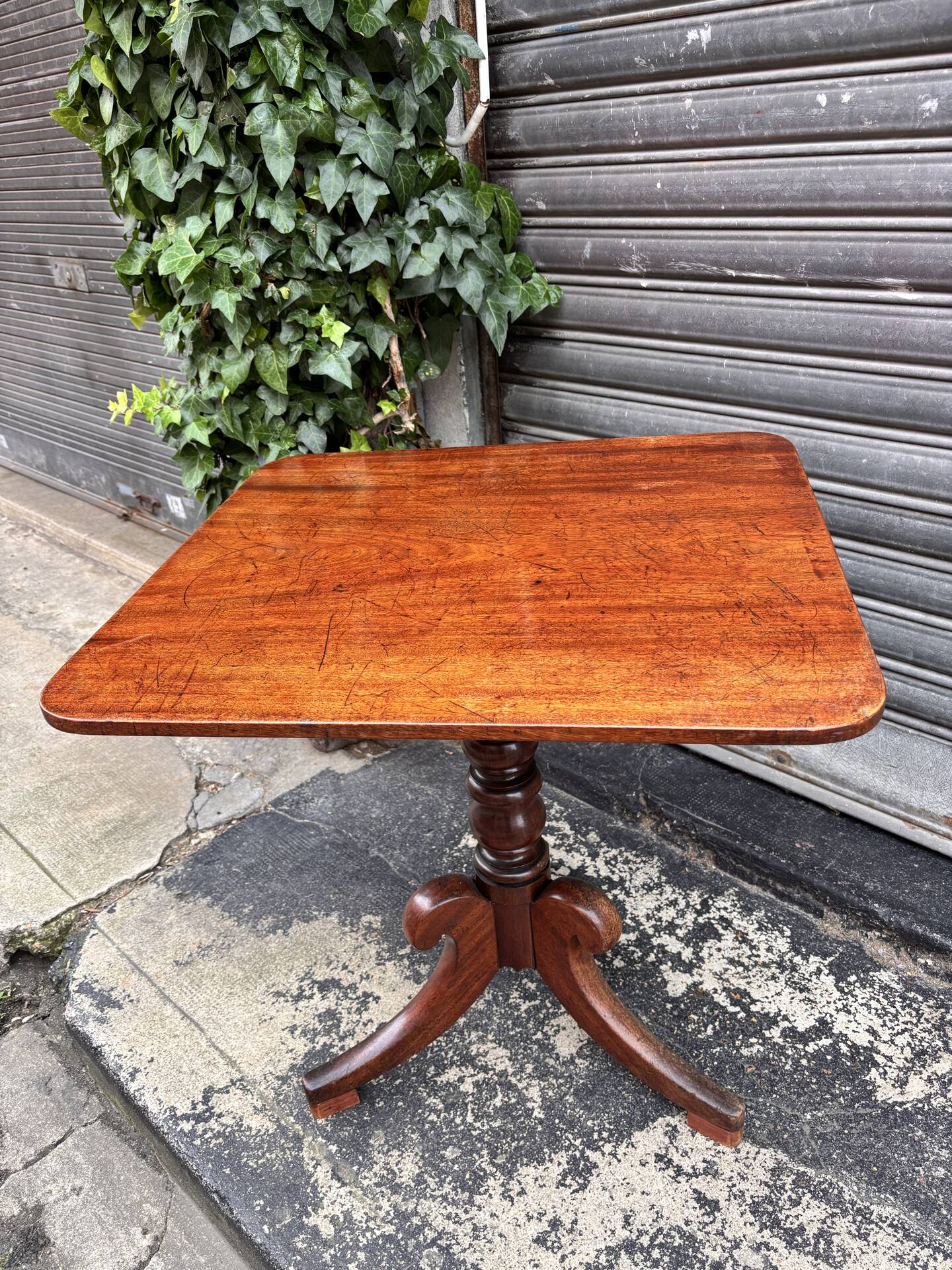 19th-century solid mahogany table with a tilting top and brass mechanism.