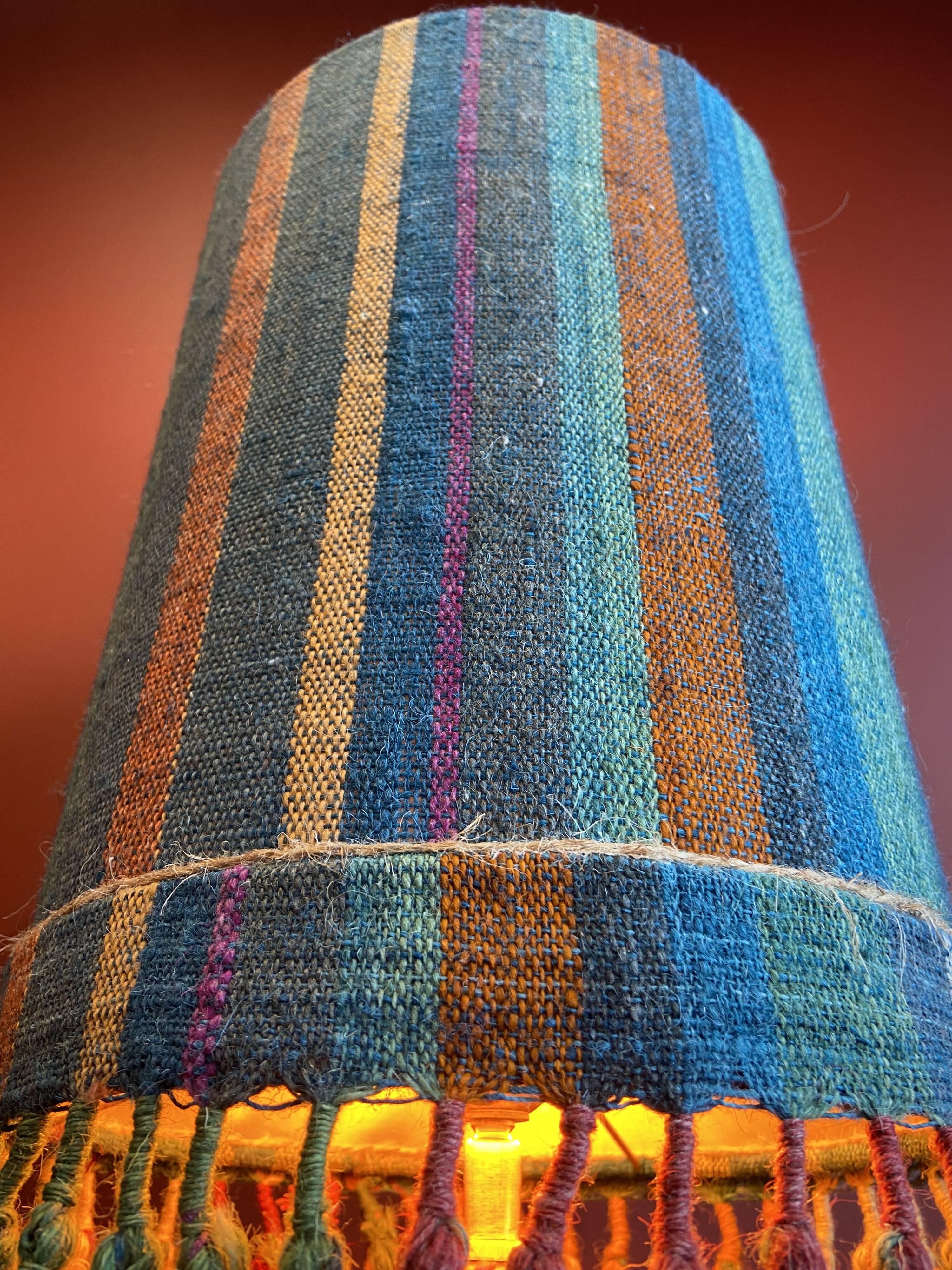 "Stoneware Bottle Lamp" with a multicoloured blue lampshade handwoven in India.