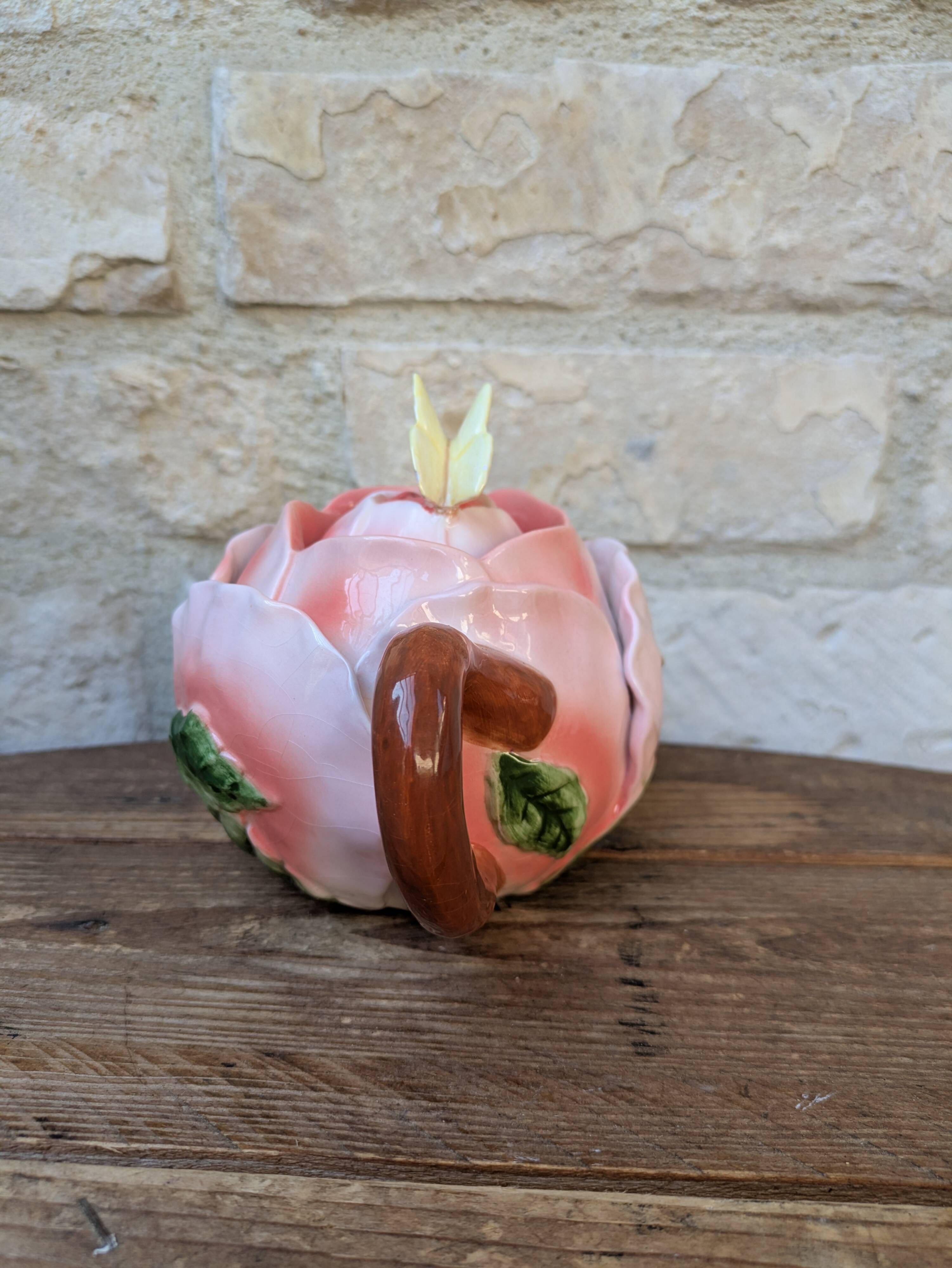 Ceramic teapot in the shape of a rose with a butterfly and raised petals.