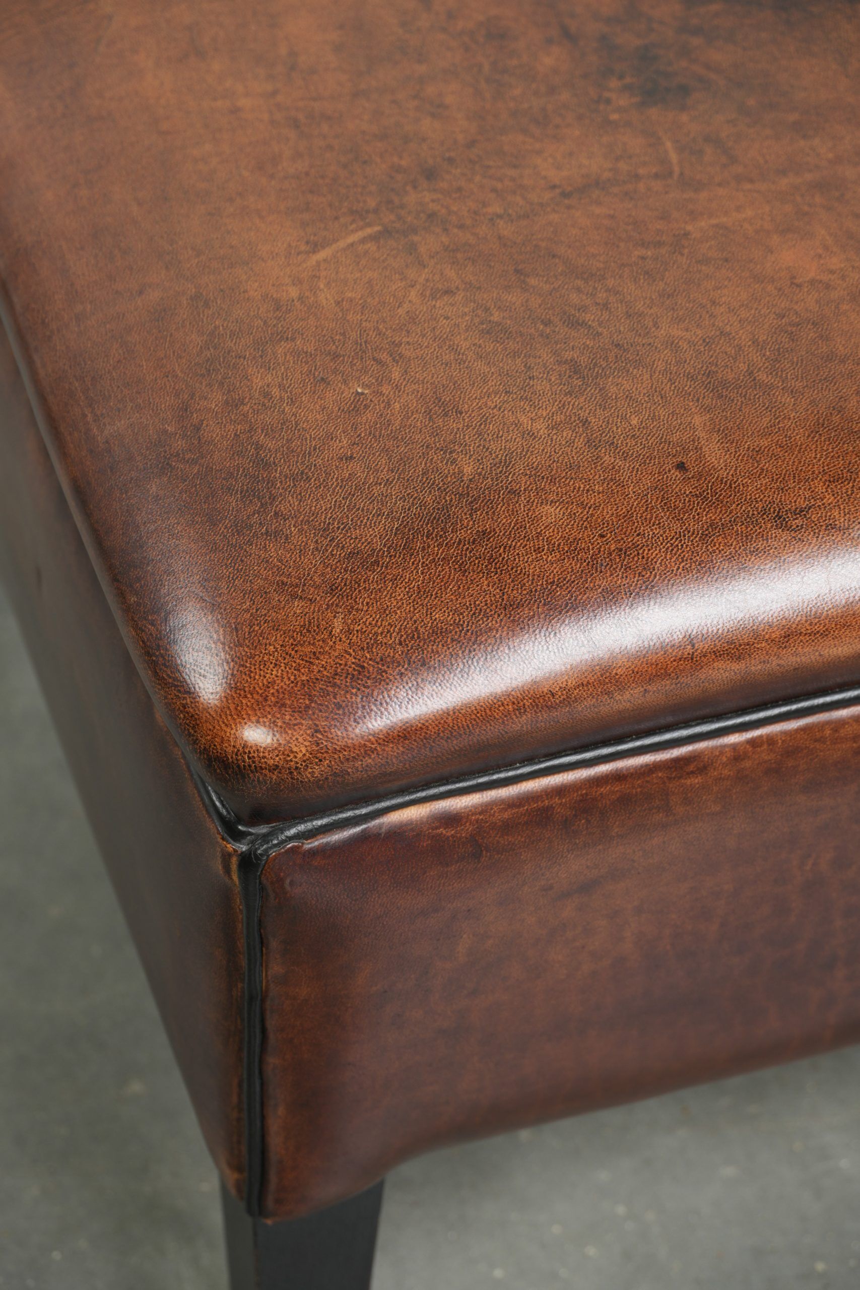 Large dark brown square ottoman made of sheepskin with black piping