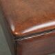 Large dark brown square ottoman made of sheepskin with black piping
