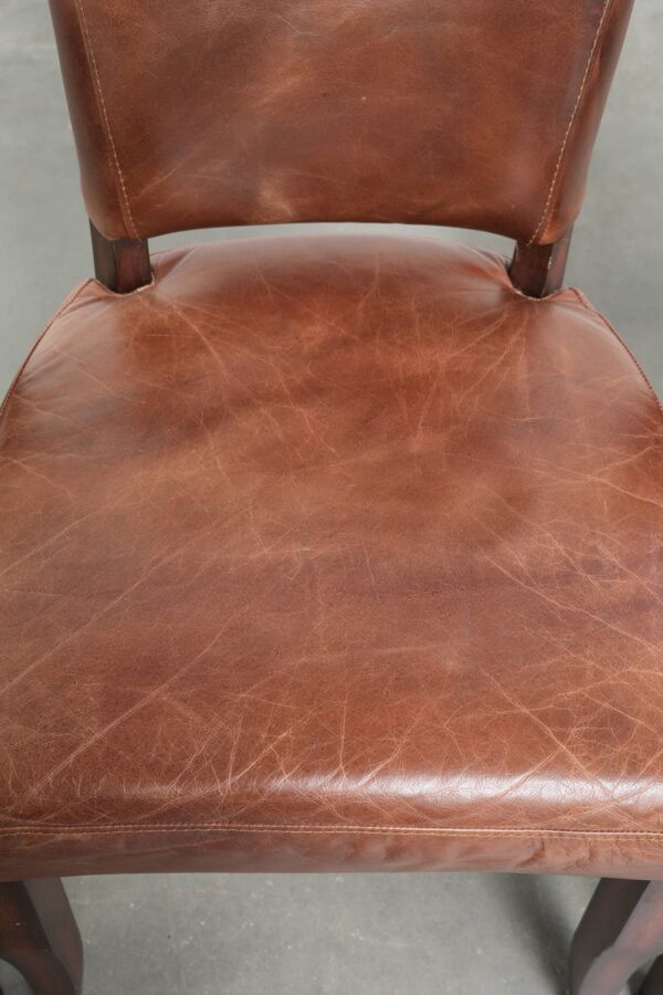 Ensemble de 4 chaises de salle à manger en cuir de vache couleur cognac avec clous décoratifs.