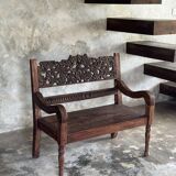 Small antique Indonesian bench in carved teak with plant and floral motifs.