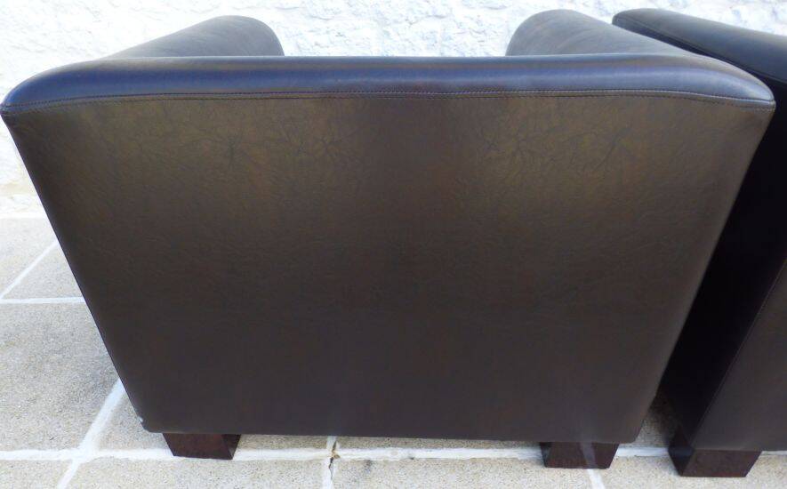 2 club armchairs with a chocolate faux leather seat and backrest and wooden legs.