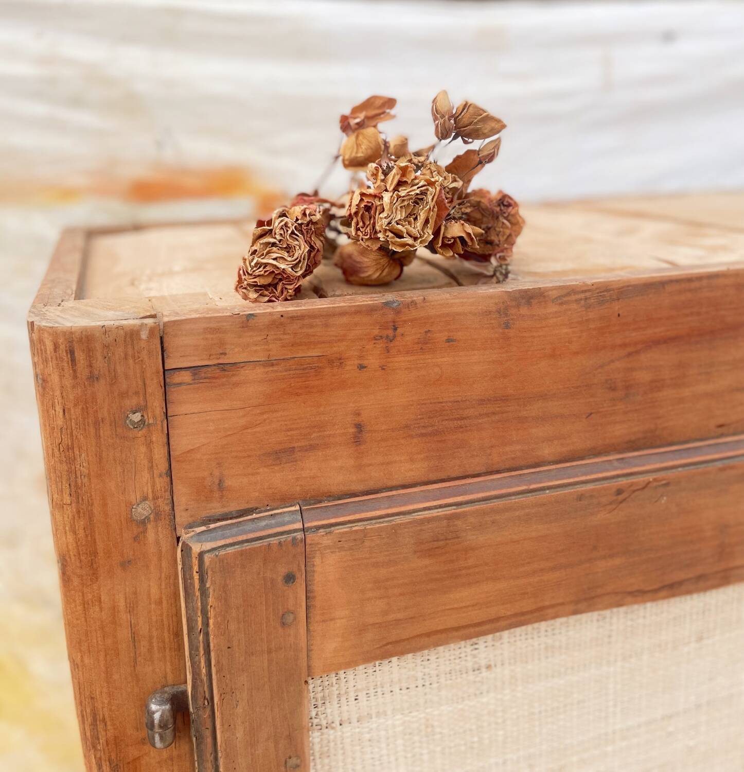 Low cabinet in raw wood and woven raffia.