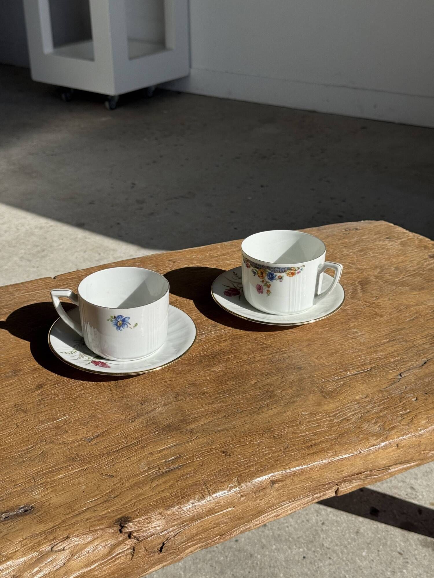 Pair of white porcelain cups from ADP France with a floral pattern and their s