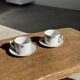 Pair of white porcelain cups from ADP France with a floral pattern and their s