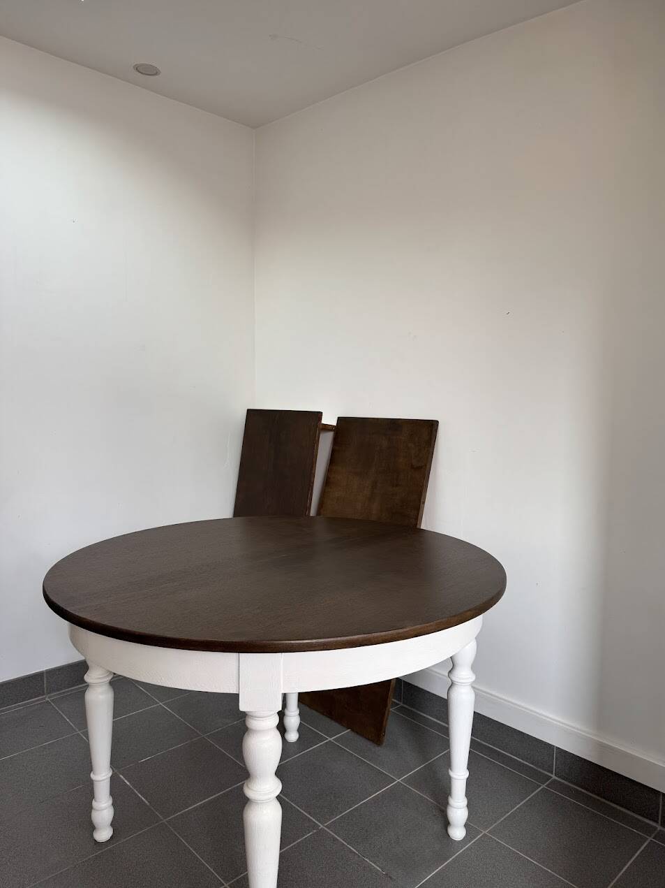 Restored solid wood round table with integrated extensions.