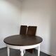 Restored solid wood round table with integrated extensions.