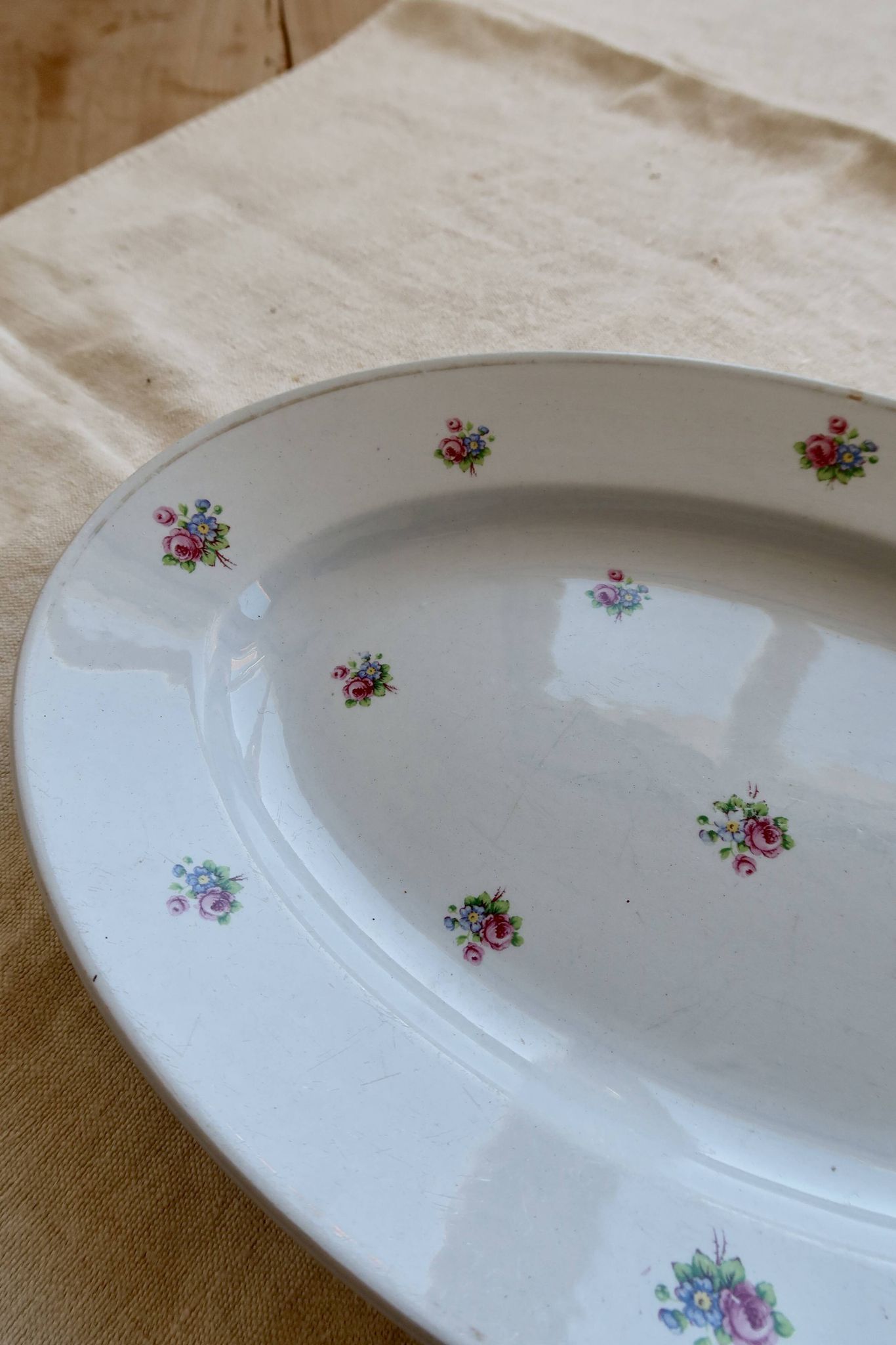 Antique oval serving dish in pale blue earthenware with a small flower design.